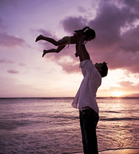 father holding daughter on the beach